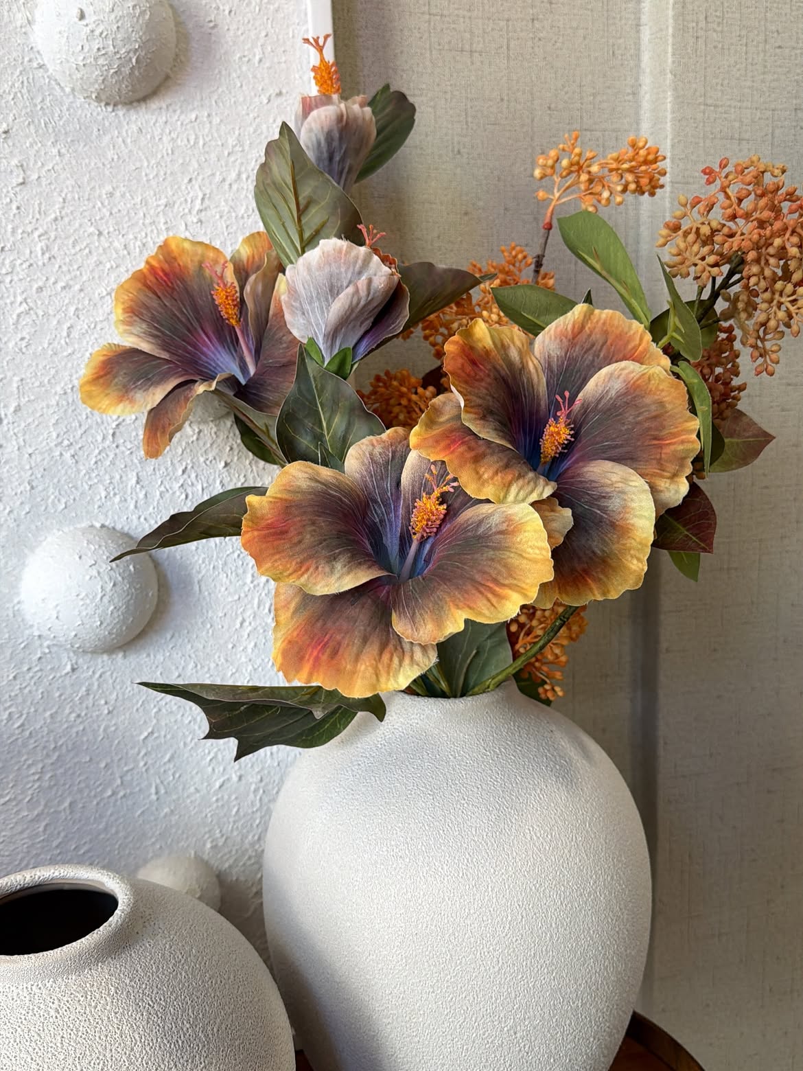 Arranjo de flores artificiais em vaso sobre aparador